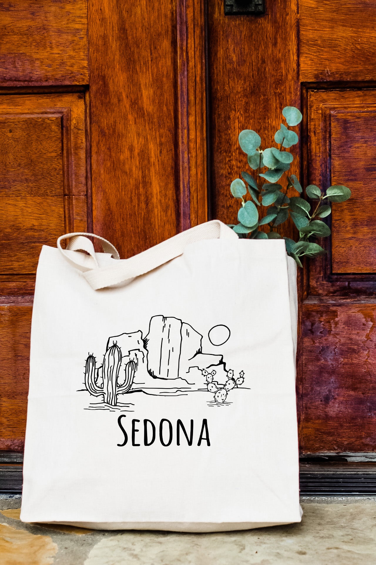 a white tote bag sitting on top of a wooden door