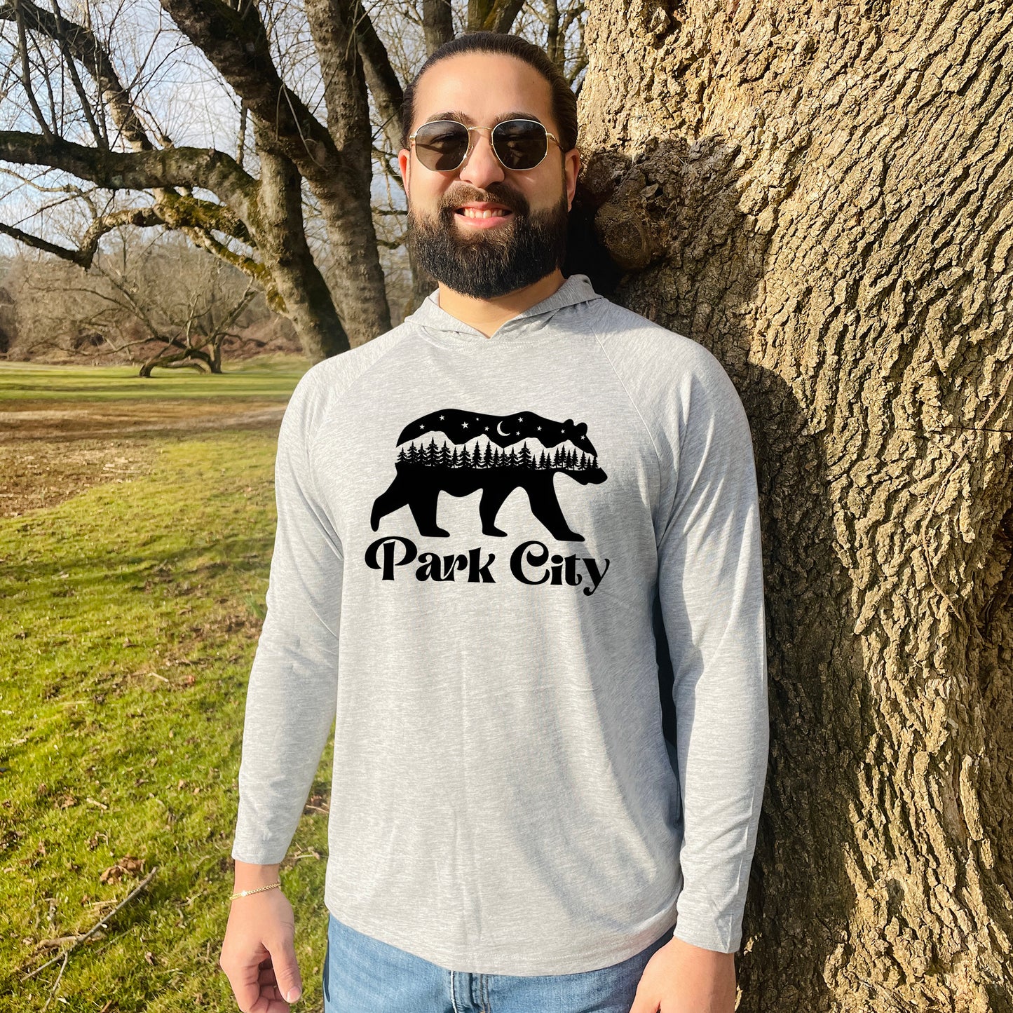 a man standing next to a tree with a bear on it