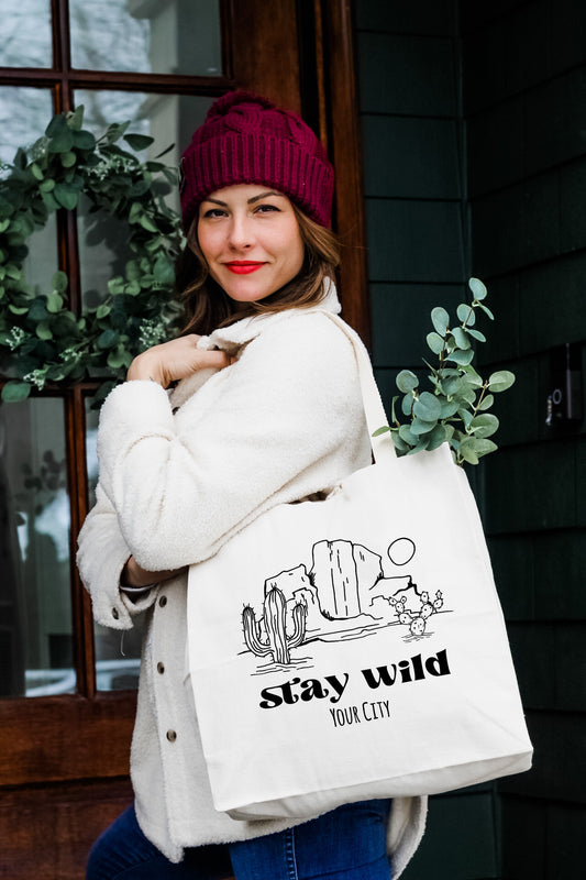 a woman holding a white bag with stay wild on it