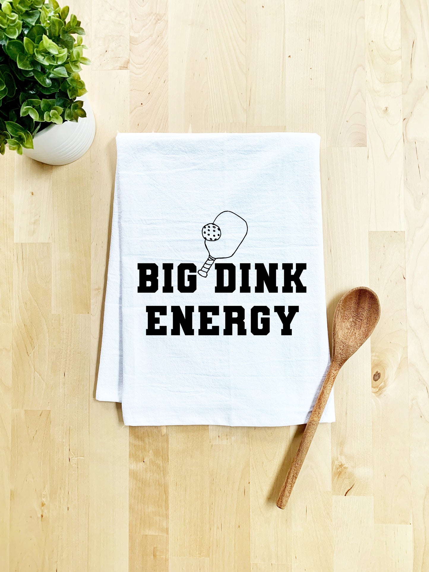 a tea towel that says bigdink energy next to a wooden spoon
