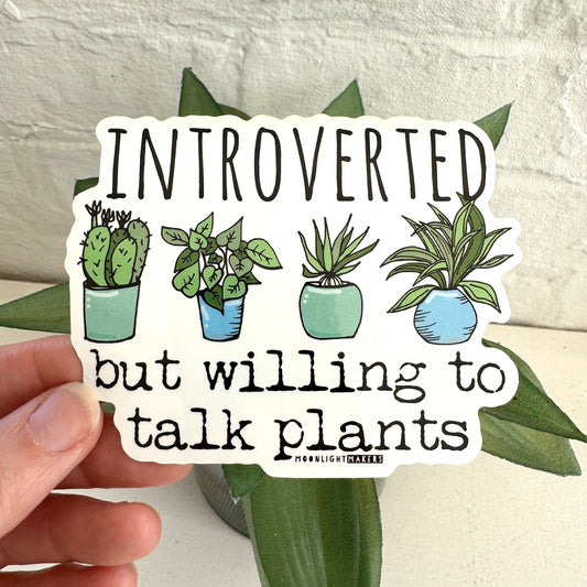 a hand holding a sticker with a picture of a potted plant