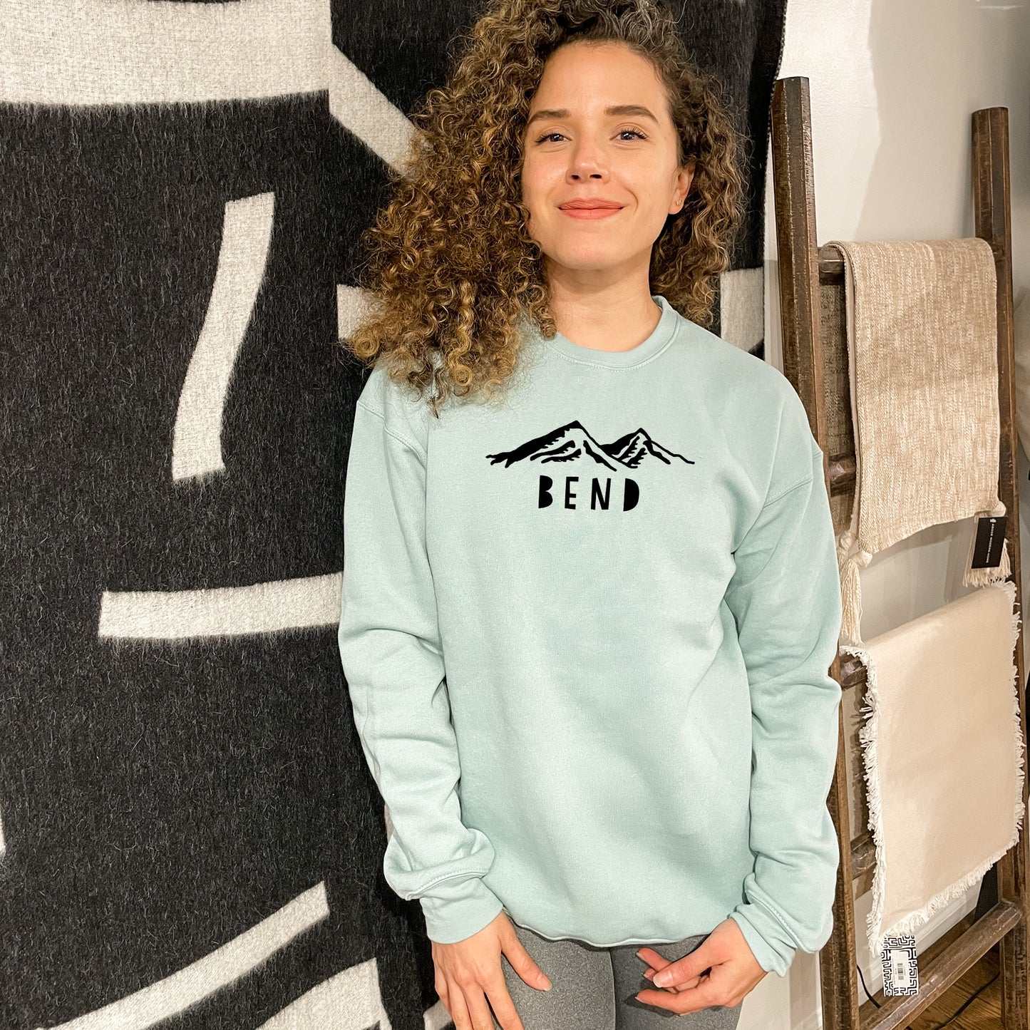 a woman standing in front of a wall wearing a sweatshirt