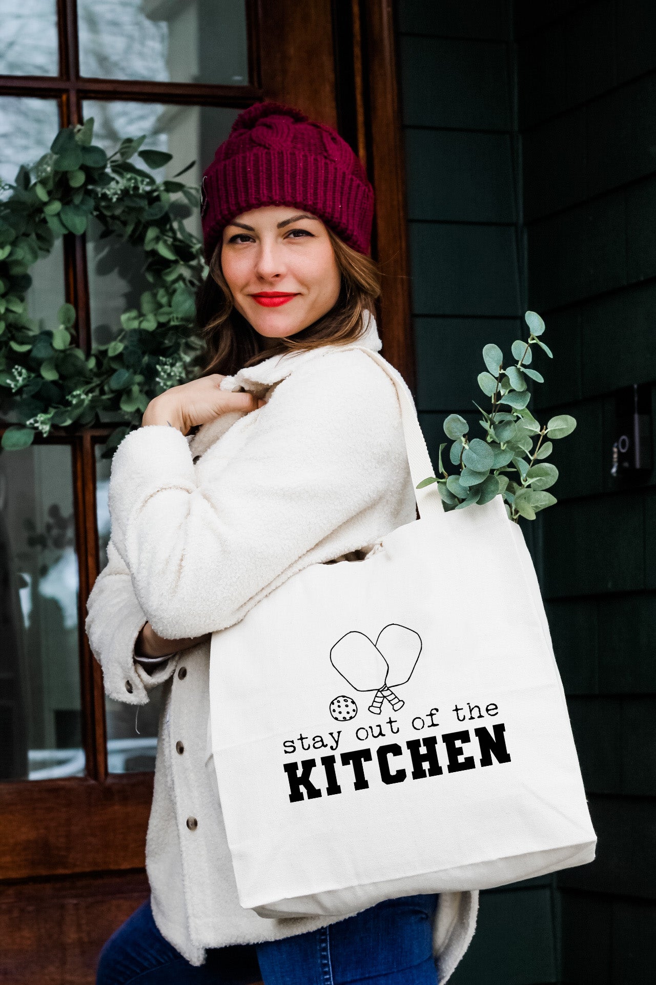 a woman carrying a white bag that says state of the kitchen