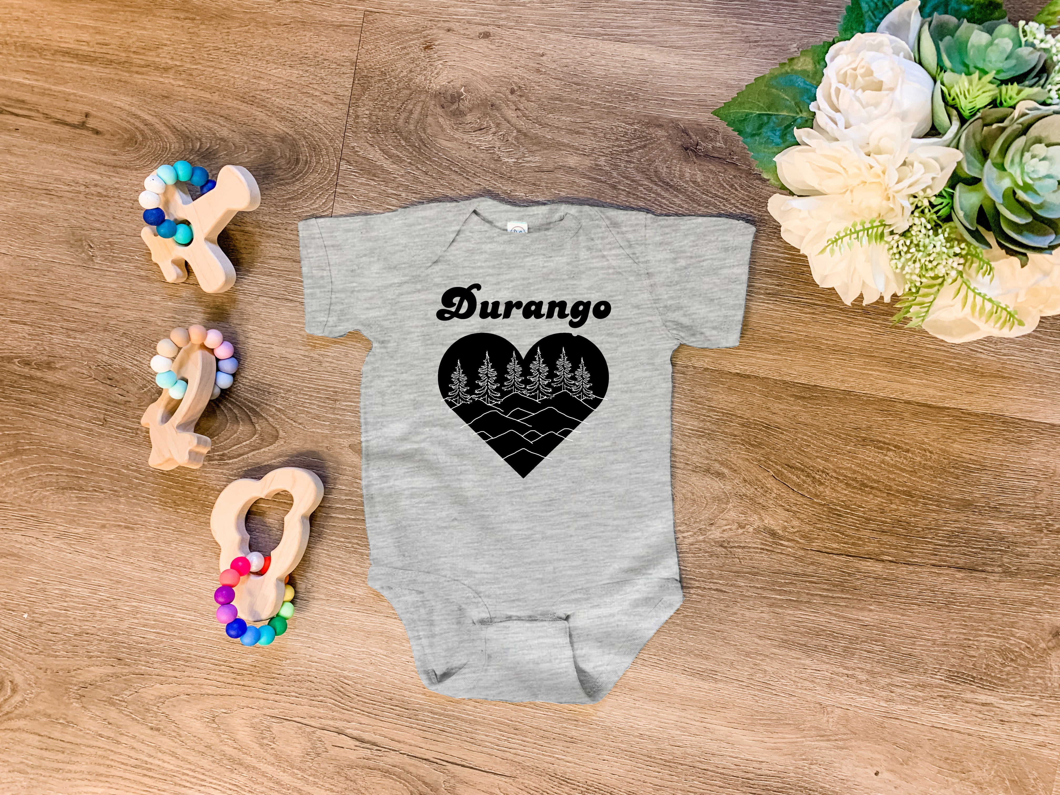 a baby bodysuit with a heart and trees on it