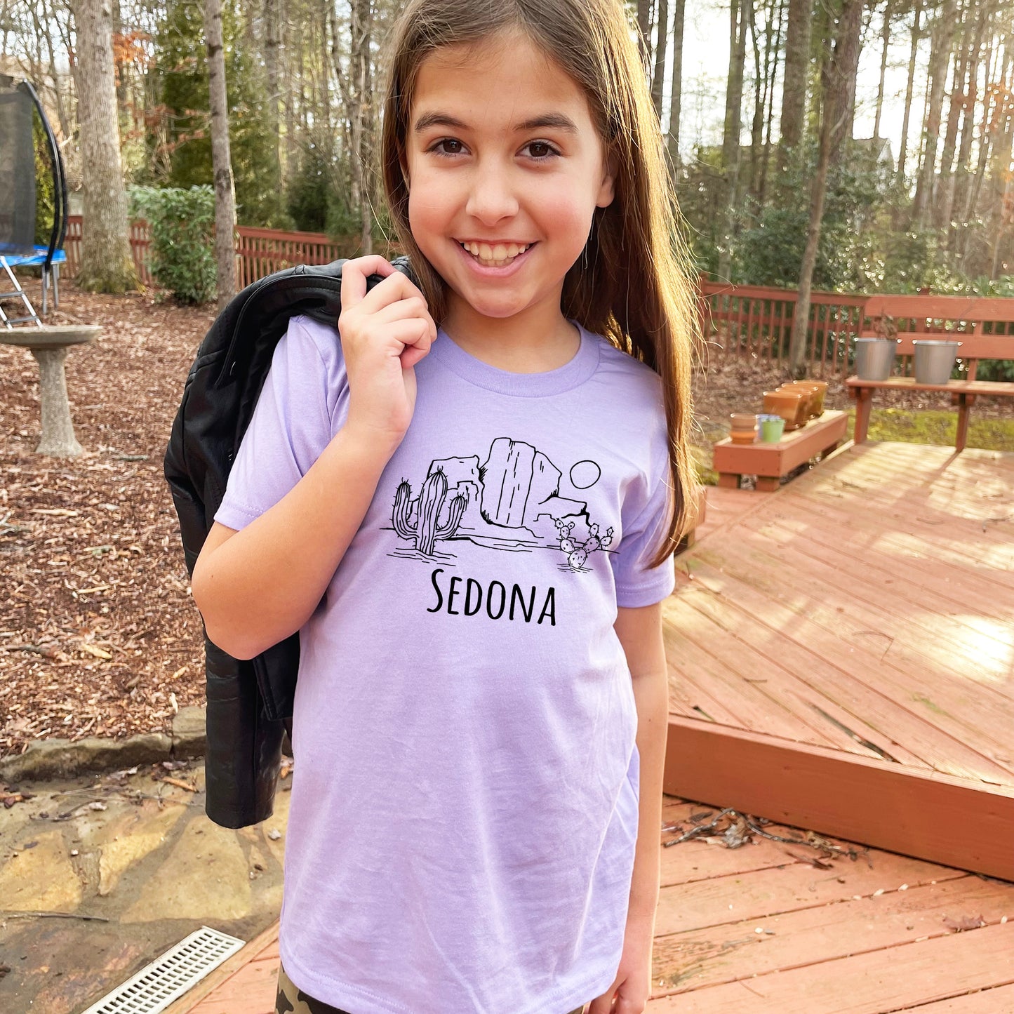 a young girl holding a backpack and smiling