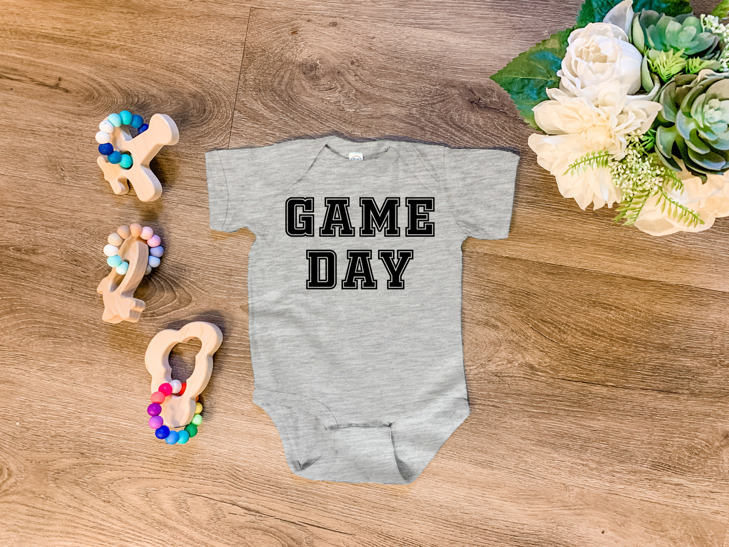 a baby bodysuit that says game day next to some pretzels