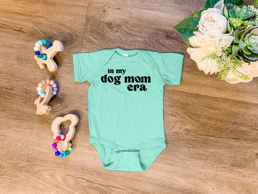 a baby bodysuit that says no my dog mom era next to a pair of