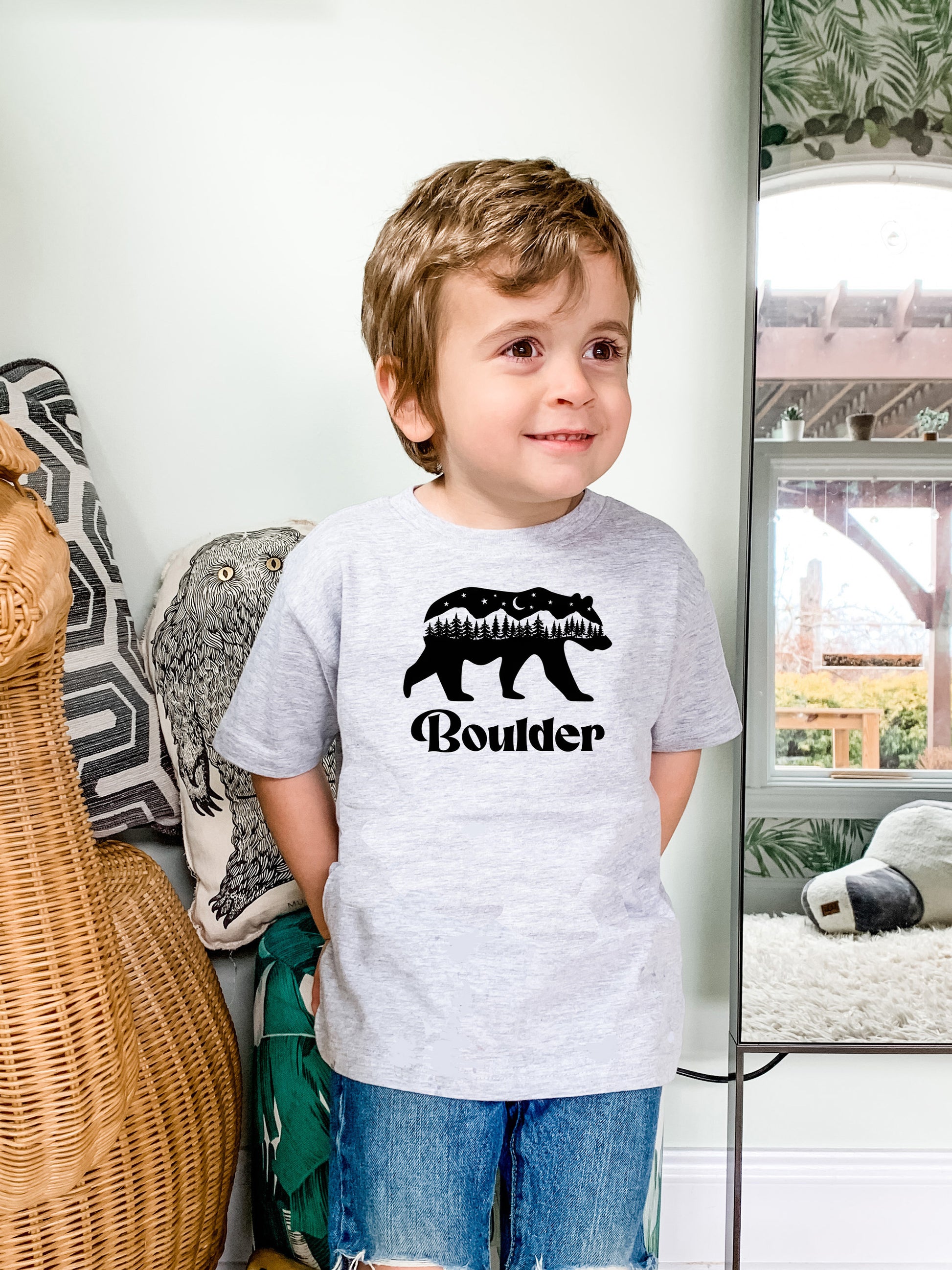 a young boy standing in front of a mirror