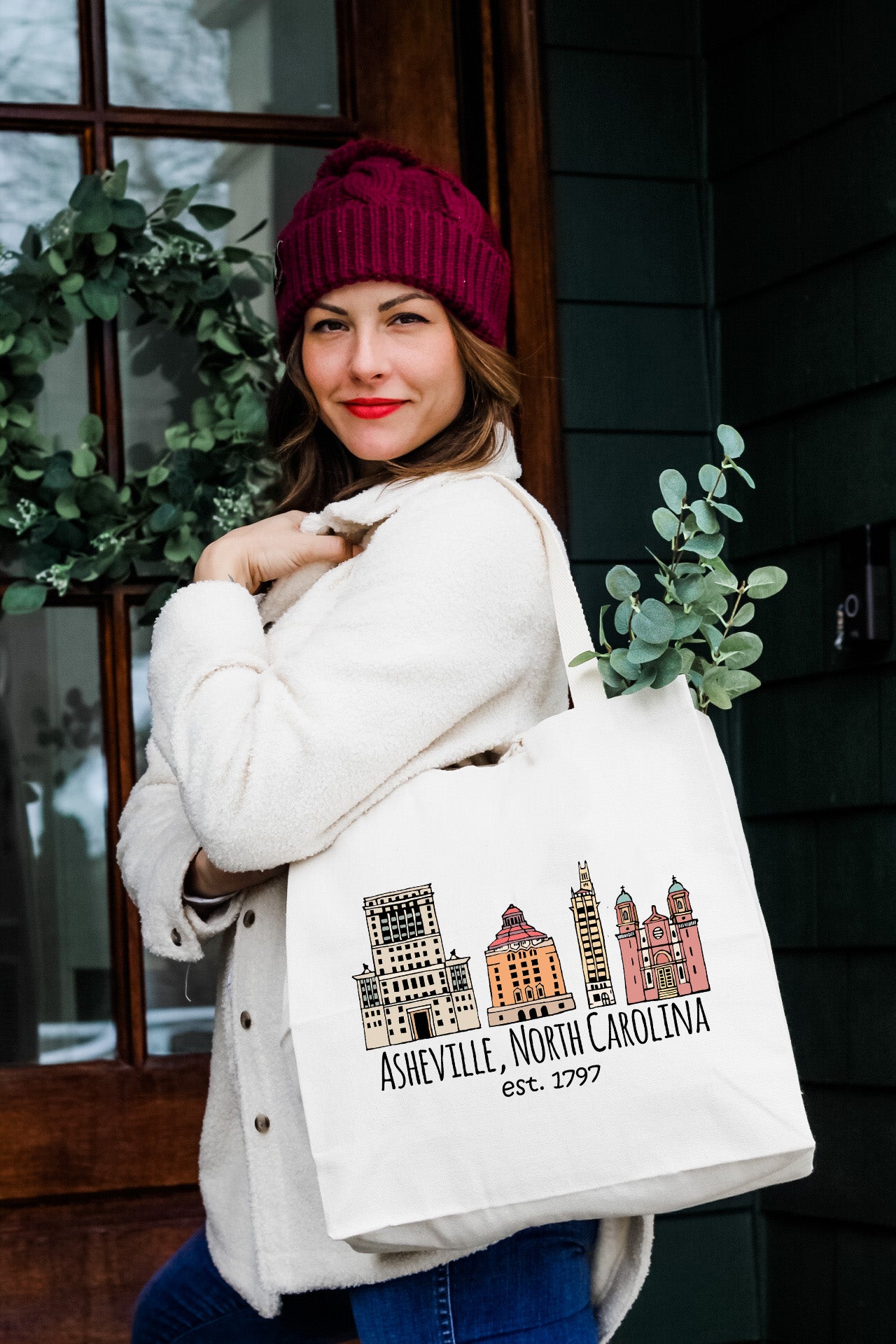 a woman carrying a white bag with a picture of a city