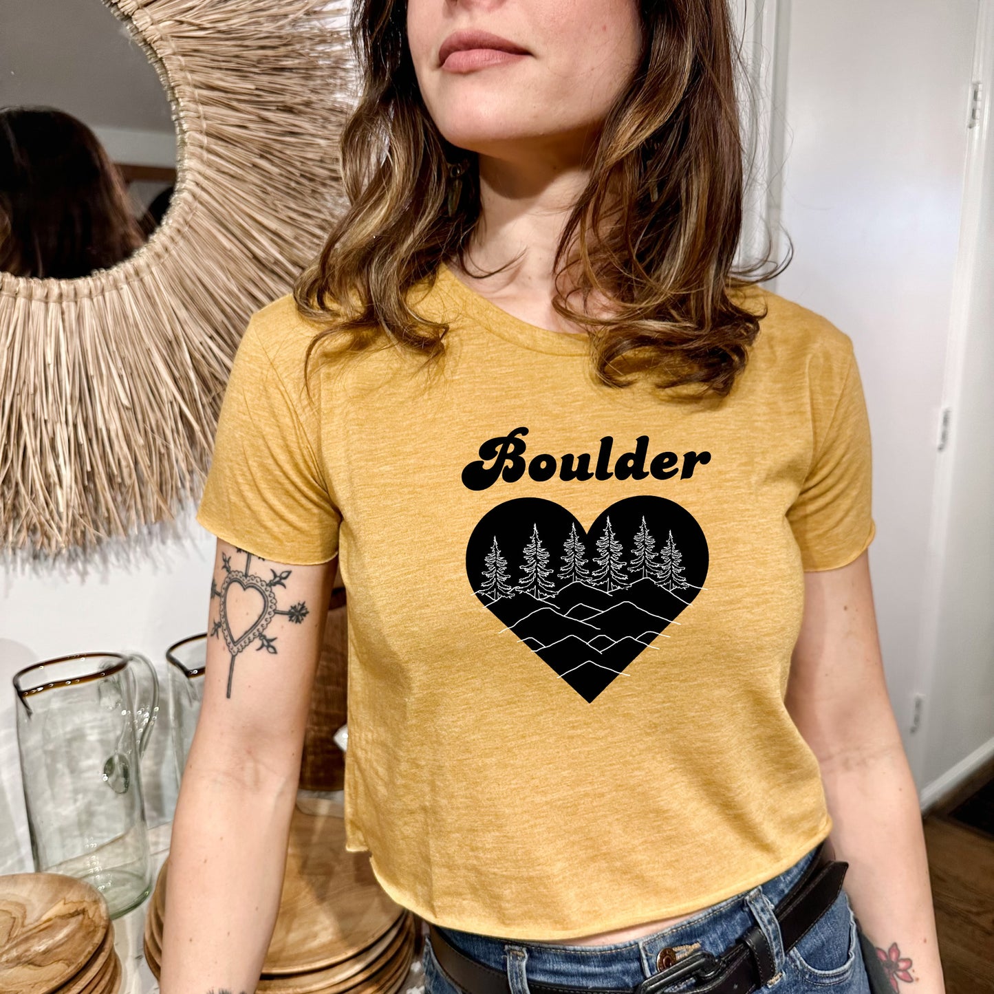 a woman wearing a yellow shirt with a heart and trees on it