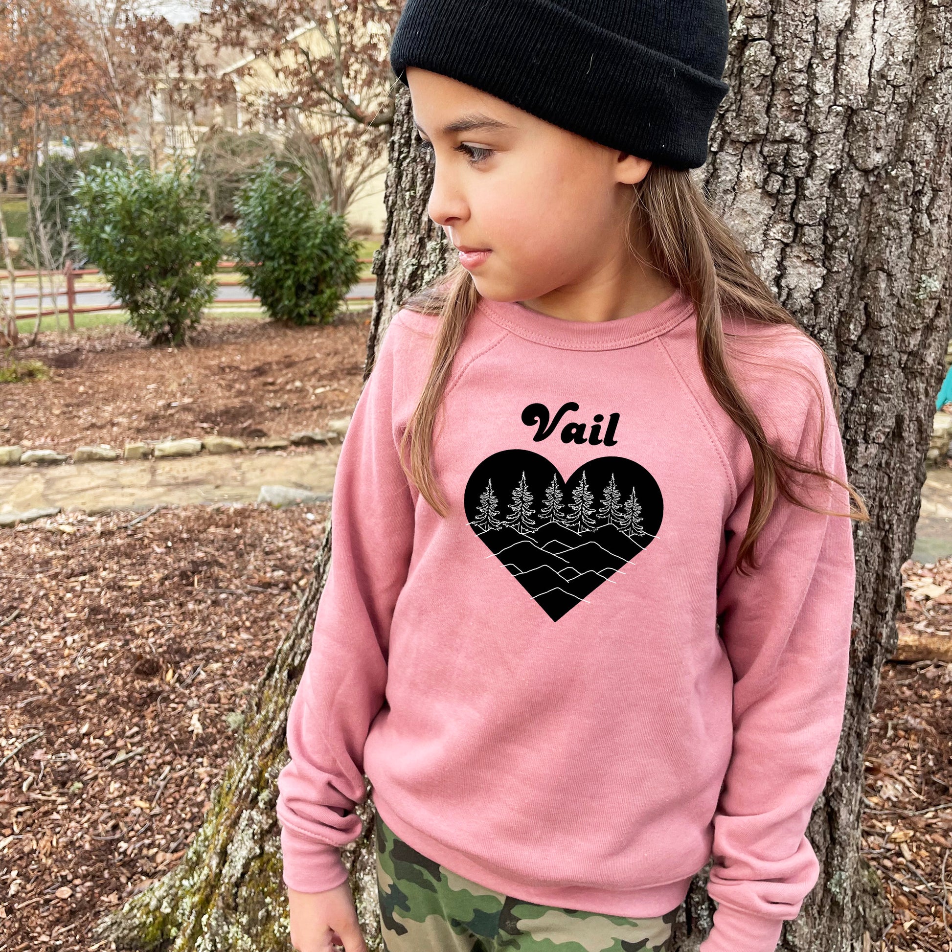 a young girl wearing a pink sweater and a black beanie